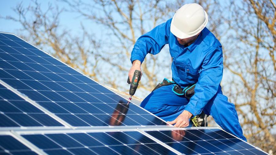 Technician fixing a solar panel on a roof